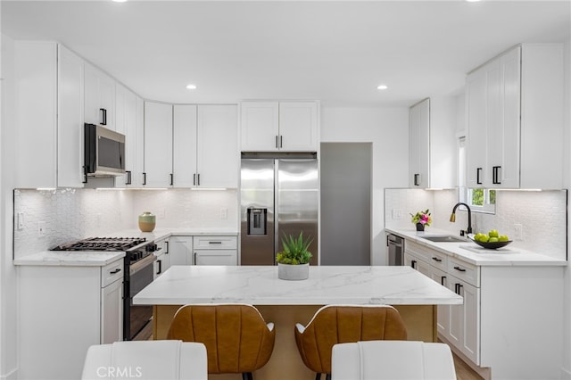 kitchen with a kitchen bar, a center island, stainless steel appliances, and white cabinetry