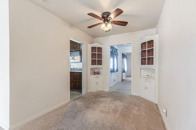 unfurnished room with ceiling fan, light colored carpet, and sink