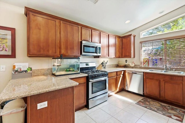 kitchen featuring sink, vaulted ceiling, light tile patterned flooring, light stone counters, and stainless steel appliances