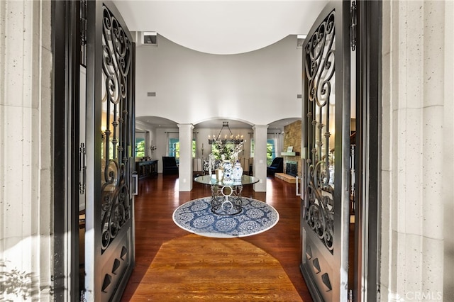 entrance foyer featuring decorative columns, a chandelier, and dark hardwood / wood-style flooring