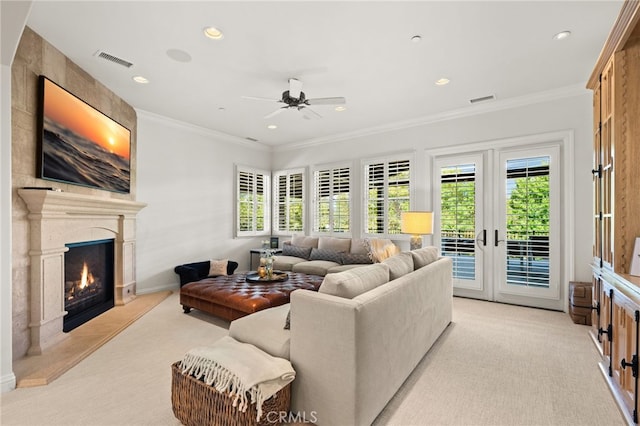 living room featuring ornamental molding, light colored carpet, a large fireplace, and ceiling fan