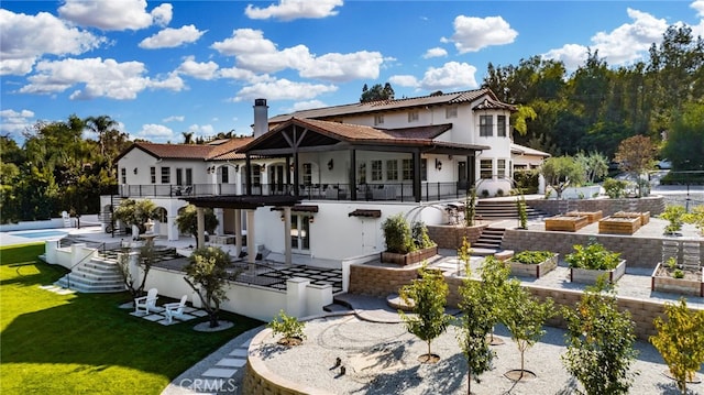 rear view of property with a patio, a yard, a pool, and a balcony