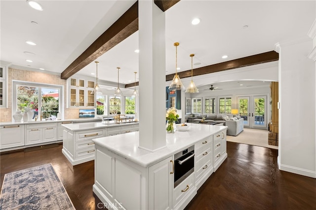 kitchen with beamed ceiling, white cabinetry, a center island, and ceiling fan