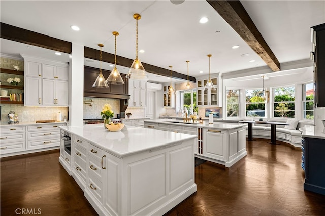 kitchen with dark parquet floors, tasteful backsplash, a kitchen island, beamed ceiling, and pendant lighting