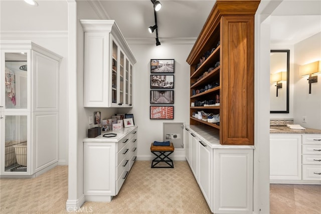 bar featuring track lighting, light stone counters, white cabinetry, crown molding, and light colored carpet