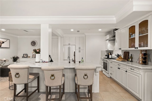 kitchen with white cabinets, light stone countertops, built in fridge, and gas range gas stove