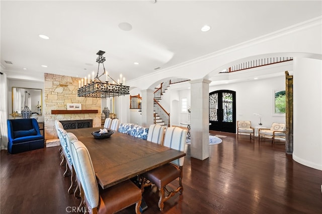 dining room with a stone fireplace, french doors, dark hardwood / wood-style floors, and crown molding