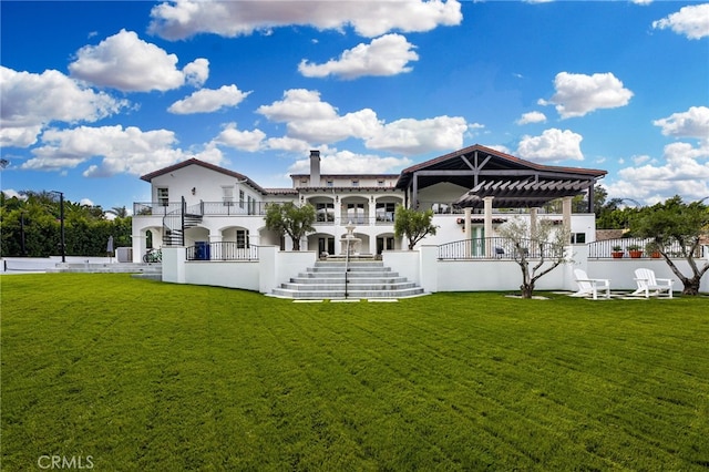 rear view of property with a yard, a pergola, and a balcony