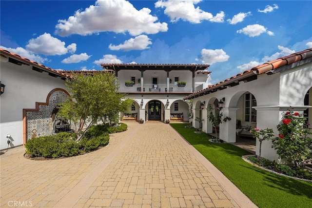 view of front of home with a balcony and a front yard