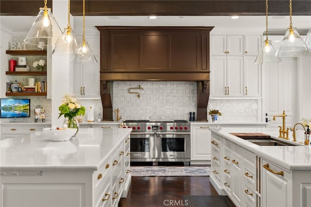 kitchen with dark wood-type flooring, sink, light stone countertops, pendant lighting, and double oven range