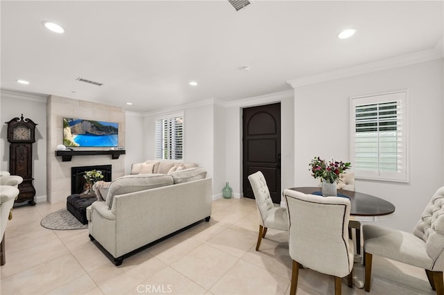 tiled living room with a tile fireplace, crown molding, and a healthy amount of sunlight