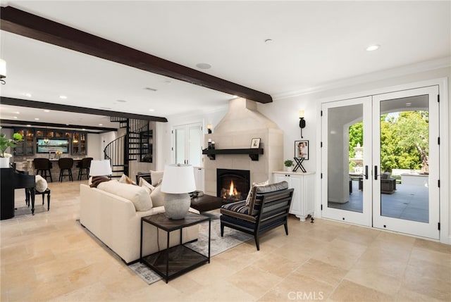 living room with french doors, beamed ceiling, a large fireplace, and crown molding