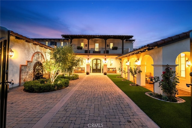 mediterranean / spanish-style home featuring french doors, a yard, and a balcony