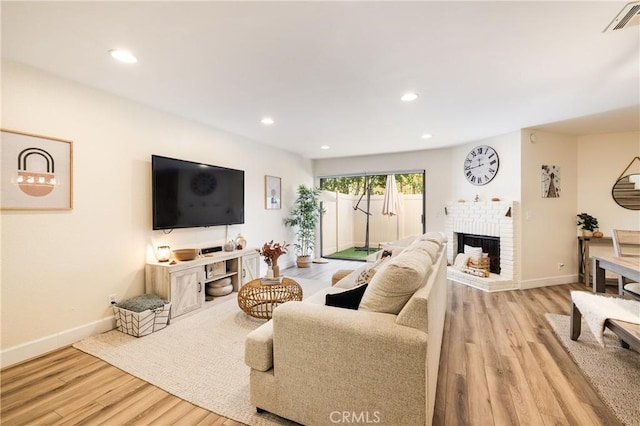 living room featuring a brick fireplace and light wood-type flooring