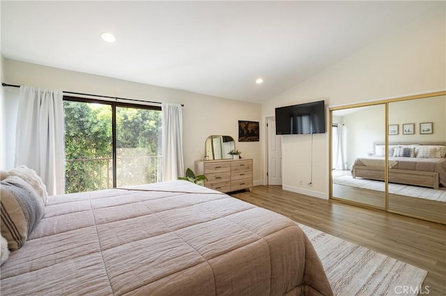 bedroom with hardwood / wood-style floors, a closet, and lofted ceiling