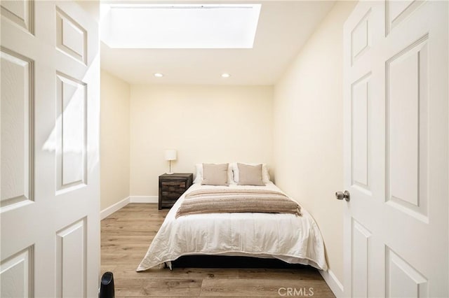 bedroom with hardwood / wood-style flooring and a skylight