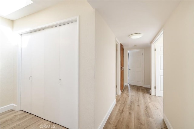 hallway featuring light hardwood / wood-style floors and a skylight