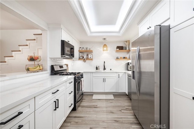 kitchen featuring tasteful backsplash, sink, white cabinetry, appliances with stainless steel finishes, and light stone counters