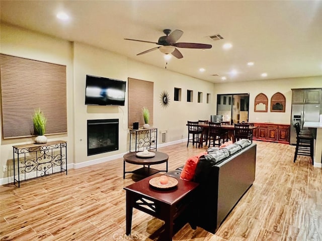 living room with light wood-type flooring and ceiling fan