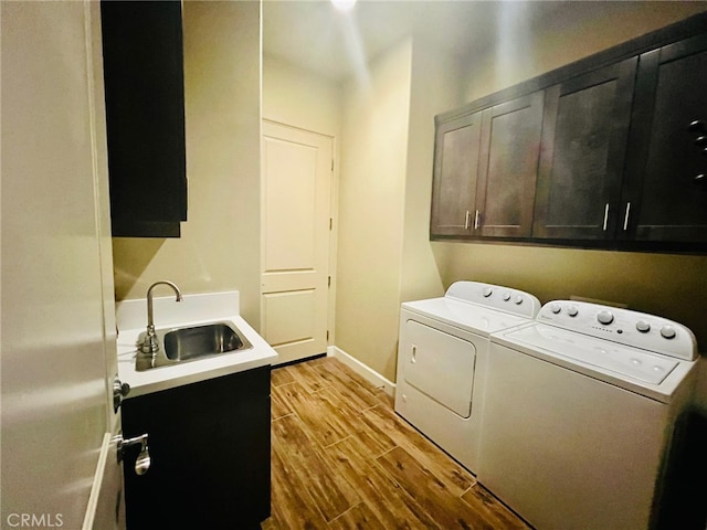 laundry room with cabinets, light wood-type flooring, sink, and washing machine and dryer