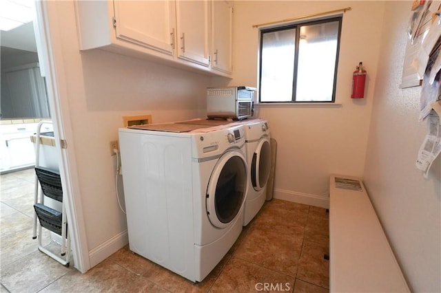 clothes washing area featuring light tile patterned floors, baseboards, cabinet space, and washing machine and clothes dryer