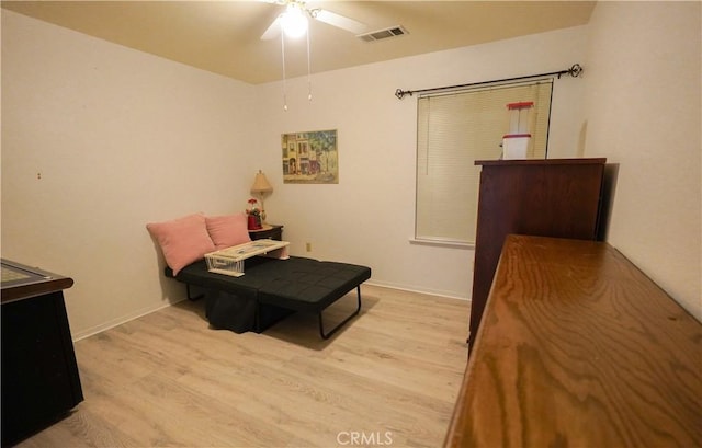 sitting room with light wood-type flooring, visible vents, baseboards, and a ceiling fan