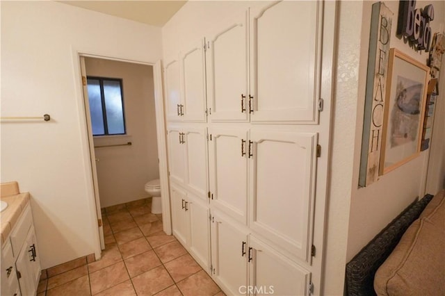bathroom featuring vanity, toilet, baseboards, and tile patterned flooring