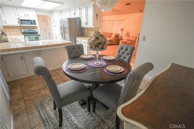 dining room featuring light tile patterned floors, baseboards, and visible vents