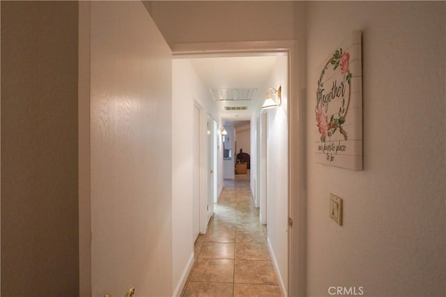 corridor featuring light tile patterned floors, visible vents, attic access, and baseboards