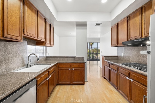 kitchen with sink, light hardwood / wood-style flooring, stainless steel appliances, light stone countertops, and decorative backsplash