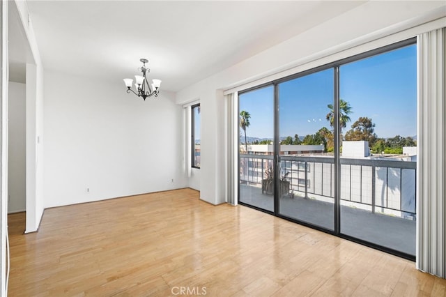 spare room featuring light hardwood / wood-style flooring and an inviting chandelier