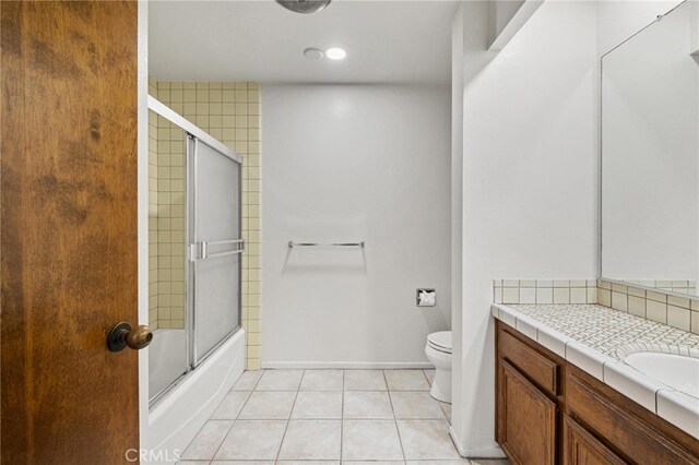 full bathroom featuring bath / shower combo with glass door, vanity, toilet, and tile patterned floors