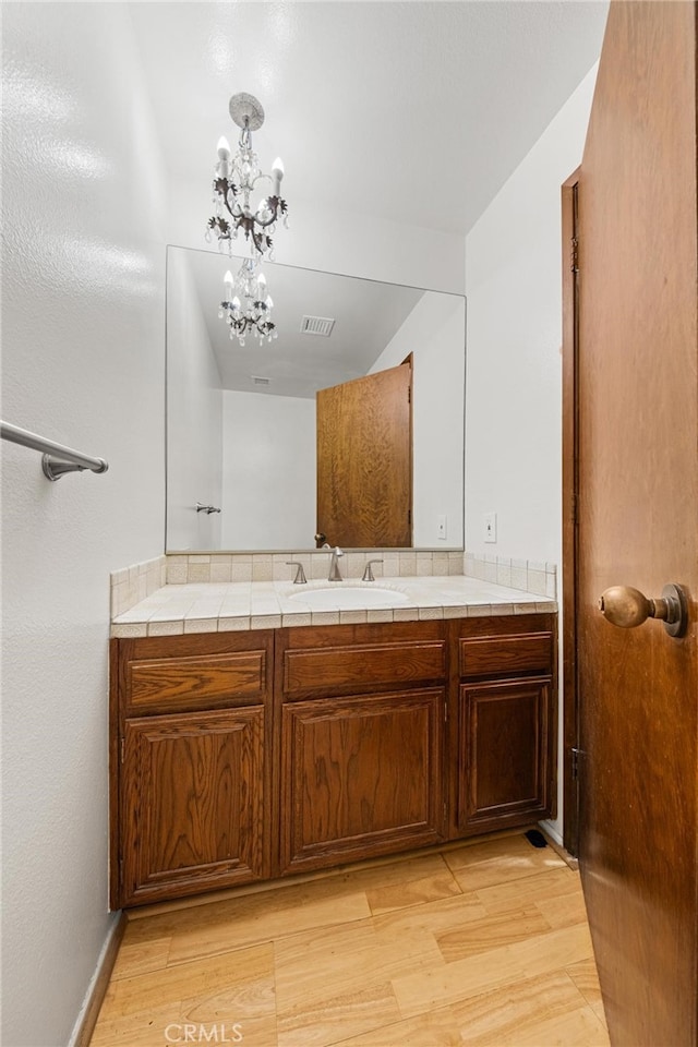 bathroom with wood-type flooring, vanity, and a notable chandelier