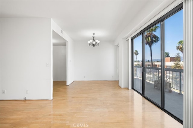 unfurnished room featuring light hardwood / wood-style flooring and a notable chandelier