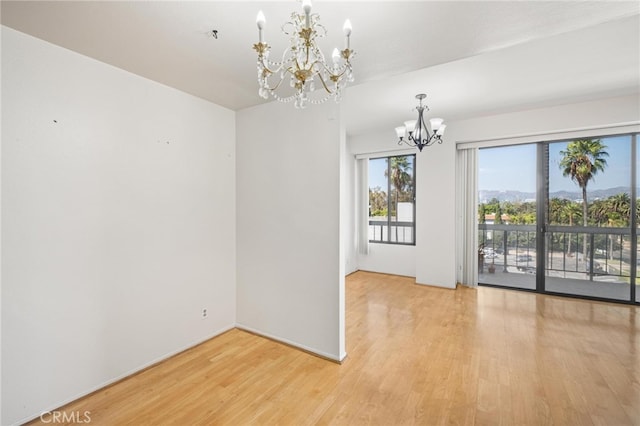 spare room featuring a notable chandelier and light hardwood / wood-style floors