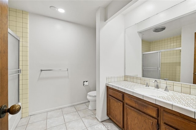 bathroom with tile patterned floors, a shower with door, vanity, and toilet