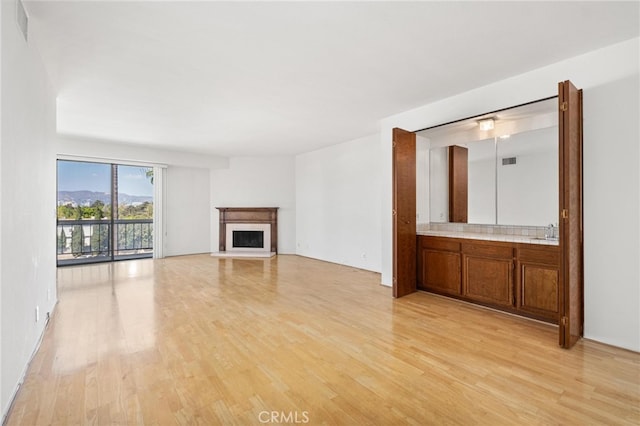 unfurnished living room featuring sink and light hardwood / wood-style flooring