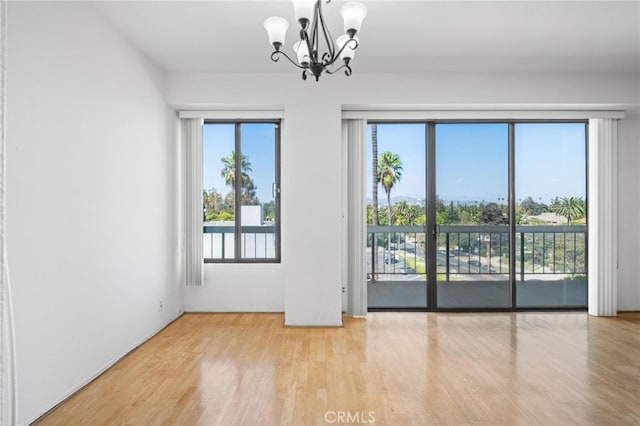 spare room featuring a chandelier and light hardwood / wood-style floors