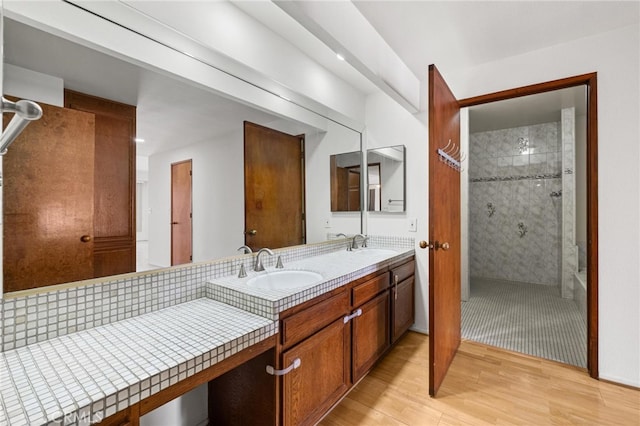 bathroom with hardwood / wood-style flooring, vanity, and tiled shower