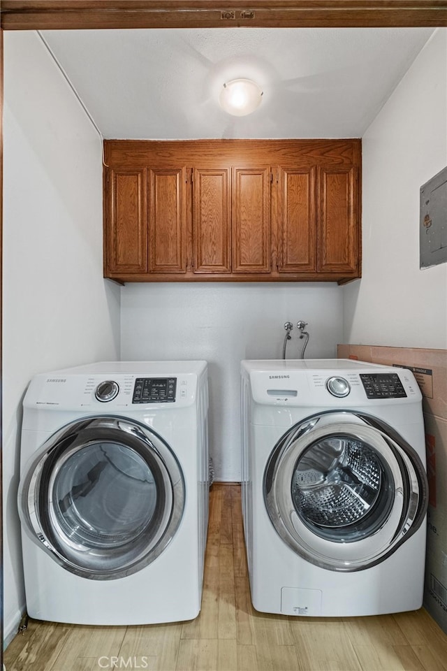 washroom with washer and clothes dryer, cabinets, and light wood-type flooring