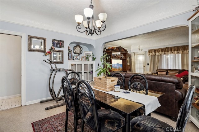 dining space with a textured ceiling, ornamental molding, and a notable chandelier