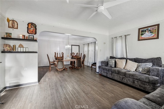 living room with a textured ceiling, ceiling fan, and dark hardwood / wood-style flooring