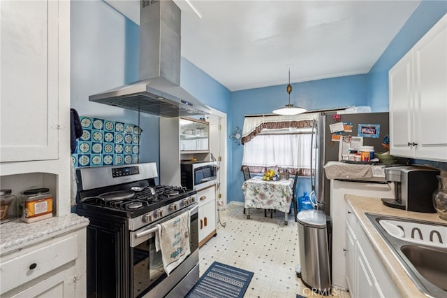 kitchen with sink, white cabinetry, hanging light fixtures, wall chimney range hood, and appliances with stainless steel finishes