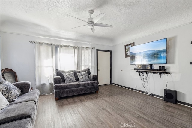 living room featuring ceiling fan, a textured ceiling, and wood-type flooring