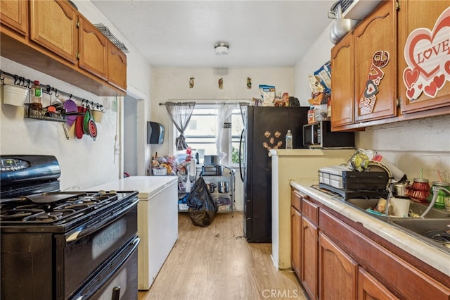 kitchen with light wood-type flooring, sink, and black gas range