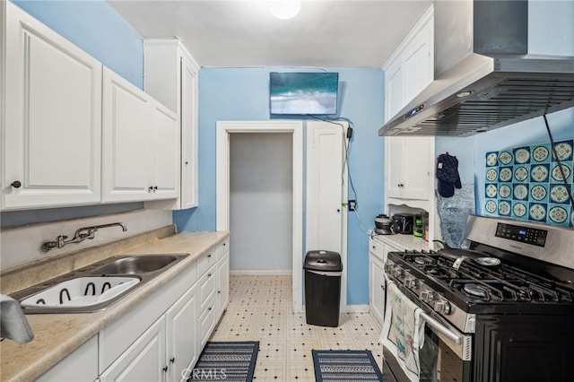 kitchen with wall chimney exhaust hood, stainless steel gas stove, sink, and white cabinetry