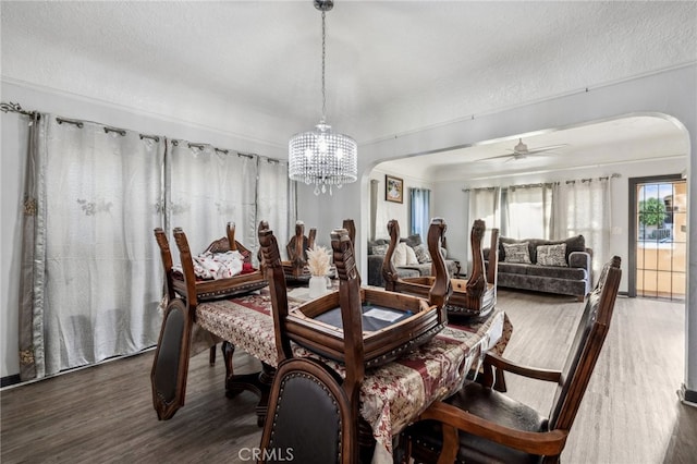 dining room with ceiling fan with notable chandelier, a textured ceiling, and dark hardwood / wood-style flooring