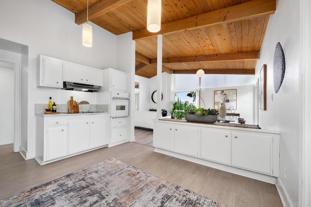 kitchen with pendant lighting, white oven, white cabinetry, vaulted ceiling with beams, and light hardwood / wood-style floors