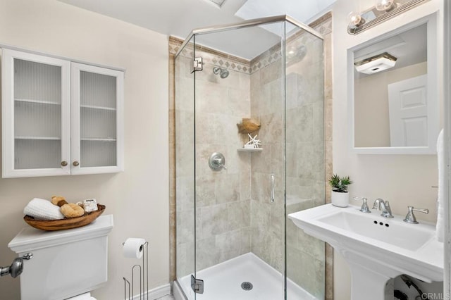 bathroom featuring sink, toilet, and a shower with door