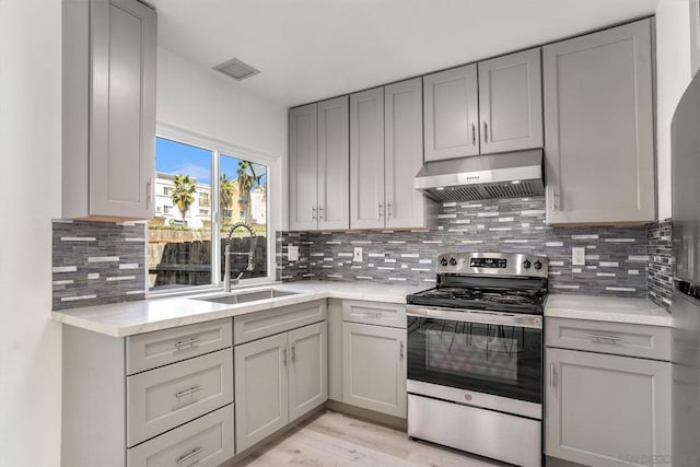 kitchen featuring decorative backsplash, gray cabinetry, stainless steel electric stove, and sink